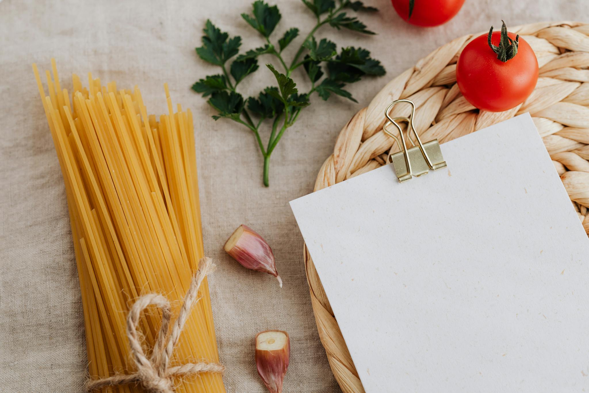 Uncooked spaghetti with tomatoes, garlic, and parsley on a rustic setup.